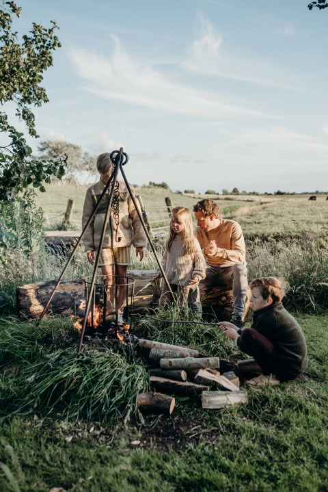 Family enjoying a campfire at Feather Down TaarTenTuin holiday park in South Holland, Netherlands.