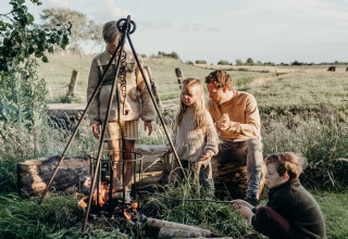 Family enjoying a campfire at Feather Down TaarTenTuin holiday park in South Holland, Netherlands.