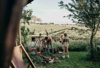 Famille autour d’un feu de camp à Feather Down TaarTenTuin, parc de vacances en Hollande méridionale, Pays-Bas, nature autour.