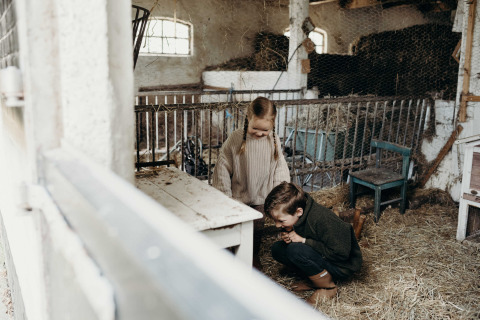Two children play together in a barn filled with hay at Feather Down TaarTenTuin holiday park in South Holland.