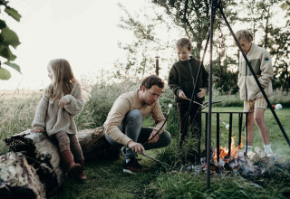 Familie grillt Marshmallows am Lagerfeuer im Feather Down TaarTenTuin Ferienpark in Südholland, Niederlande.