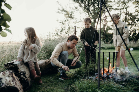 Famiglia che tosta marshmallow accanto al fuoco al Feather Down TaarTenTuin in Olanda Meridionale, Paesi Bassi.