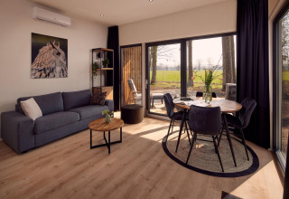 Salón moderno en la villa Holiday Amalia 2 en Hofparken Wiltershaar, Países Bajos, con grandes ventanas y vista natural.