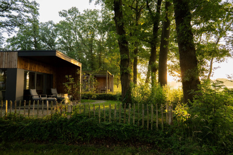 Træomgivet lodge ved solnedgang med moderne træfacade, terrasse og hegn, Holiday villa Amalia 2, Nederlandene.