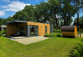 Moderne feriebolig med træfacade og udendørs sauna i grønne omgivelser på Hofparken Wiltershaar, Holland.