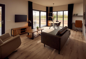 Salon moderne et accessible en fauteuil roulant dans une villa de vacances avec vue sur la nature verdoyante.