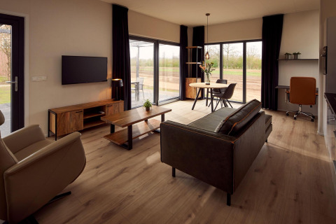 Rollstuhlgerechtes Wohnzimmer in einem Ferienhaus mit moderner Einrichtung und großen Fenstern zur Natur.