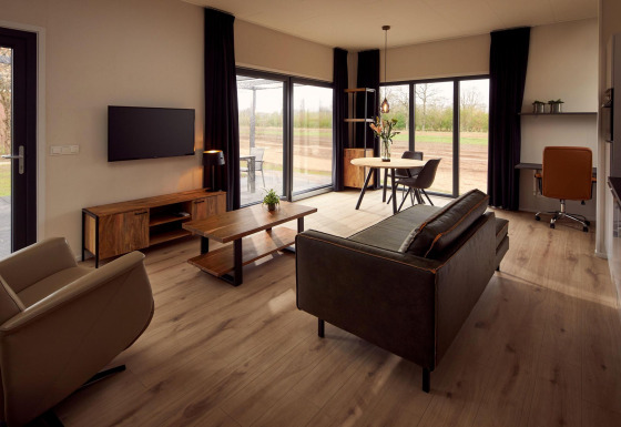 Salon moderne et accessible en fauteuil roulant dans une villa de vacances avec vue sur la nature verdoyante.