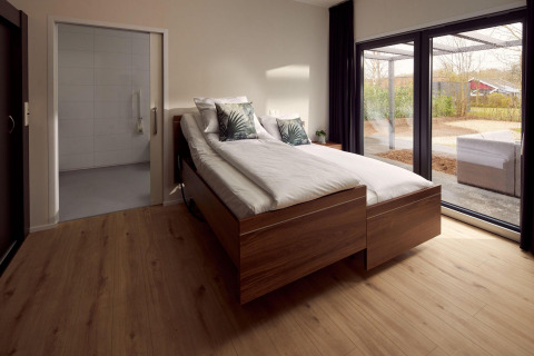 Chambre adaptée en fauteuil roulant, parquet, lits jumeaux et grandes fenêtres sur terrasse aux Pays-Bas.