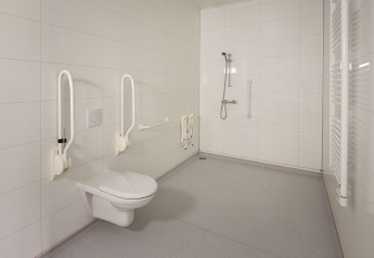 Handicapvenligt badeværelse med støttehåndtag, bruser og væghængt toilet i Holiday villa Amalia 2.