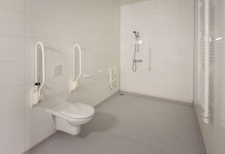 Accessible bathroom with grab bars, wall-mounted toilet and open shower at Holiday villa Amalia 2.