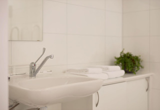 Baño adaptado en Holiday villa Amalia 2, Hofparken Wiltershaar, Países Bajos, con lavabo y toallas blancas.