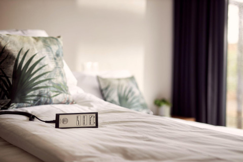 Letto con cuscini tropicali e telecomando in Holiday villa Amalia 2, accessibile a Hofparken Wiltershaar.