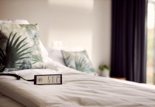 Cama con cojines tropicales y mando a distancia en Holiday Villa Amalia 2, accesible en Hofparken Wiltershaar.