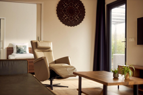Salón de Holiday villa Amalia 2 en Hofparken Wiltershaar, Países Bajos, con sillón y mesa de madera.