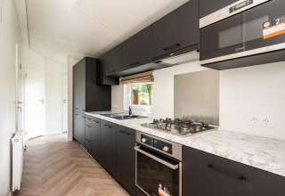 Moderne zwarte keuken met marmeren werkblad in Cozy Chalet te Veluwepark de Bosgraaf, Nederland.