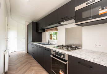 Moderne sort køkken med marmor bordplade på Cozy Chalet i Veluwepark de Bosgraaf, Holland.