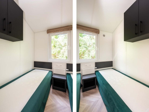 Camas gemelas en una habitación luminosa y compacta con ventana y armarios en Cozy Chalet, Veluwepark de Bosgraaf.
