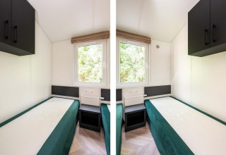 Twee bedden in een lichte, compacte kamer met raam en kasten in Cozy Chalet bij Veluwepark de Bosgraaf.