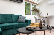 Moderne woonkamer in Cozy Chalet, Veluwepark de Bosgraaf, met groene bank en stijlvolle tafel.
