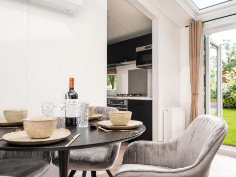 Mesa de comedor con vajilla, vino y sillas elegantes en Cozy Chalet de Veluwepark de Bosgraaf, Países Bajos.