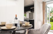 Eettafel met servies, wijn en comfortabele stoelen in Cozy Chalet op Veluwepark de Bosgraaf, Nederland.