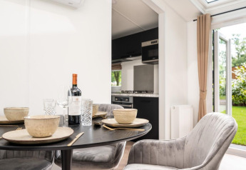 Spisebord med borddækning, vin og komfortable stole i Cozy Chalet på Veluwepark de Bosgraaf, Holland.