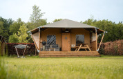 Safari-teltet Villatent Cottage på Camping 't Geuldal i Nederlandene med veranda og grønne omgivelser.