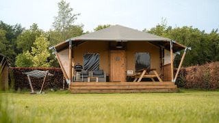 Safaritent Villatent Cottage op Camping 't Geuldal in Nederland met veranda en uitzicht op het gras.