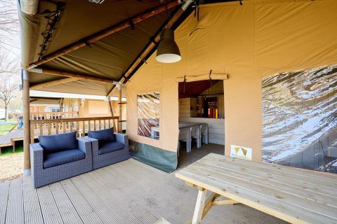 Area lounge coperta della Villatent Cottage al Camping 't Geuldal, Paesi Bassi, con sedie e tavolo.