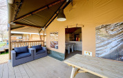 Covered outdoor lounge at Villatent Cottage, Camping 't Geuldal, Netherlands, with chairs and table.