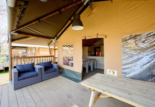 Area lounge coperta della Villatent Cottage al Camping 't Geuldal, Paesi Bassi, con sedie e tavolo.