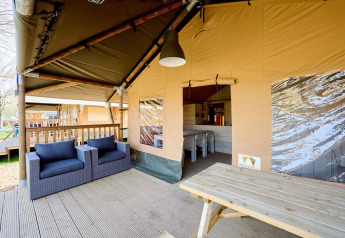 Covered outdoor lounge at Villatent Cottage, Camping 't Geuldal, Netherlands, with chairs and table.