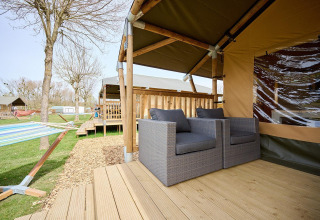 Terras van safaritent met loungestoelen en hangmat op Camping 't Geuldal, Nederland.
