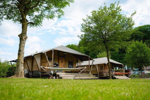 Tenda safari Villatent Cottage al Camping 't Geuldal, Paesi Bassi, con amache e alberi verdi.