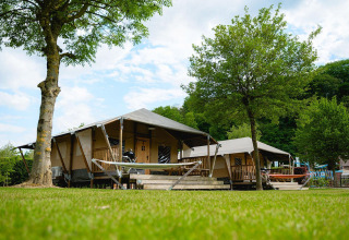 Tenda safari Villatent Cottage al Camping 't Geuldal, Paesi Bassi, con amache e alberi verdi.