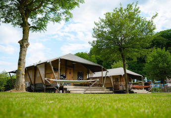 Safari tent Villatent Cottage at Camping 't Geuldal in the Netherlands, with hammocks and green trees.