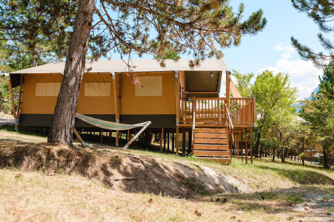 Villatent Nomad op Camping La Presqu’île in Frankrijk, houten terras, hangmat en groene omgeving.