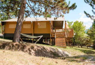 Villatent Nomad op Camping La Presqu’île in Frankrijk, houten terras, hangmat en groene omgeving.