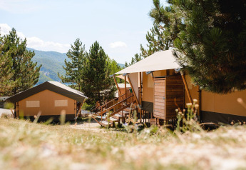 Lodges Villatent Nomad au Camping La Presqu’île en France, entourés d’arbres et de montagnes.