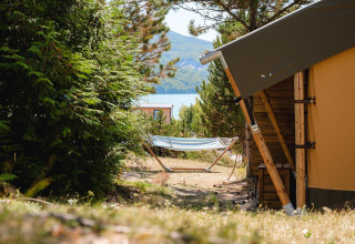 Hamaca y tienda de campaña en Villatent Nomad, Camping La Presqu’île, Francia, con vista al lago y montañas.