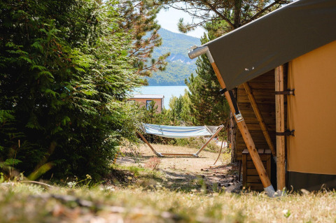 Hammock and tent setup at Villatent Nomad, Camping La Presqu’île, France, with mountain and lake view.