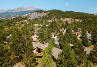 Vista aérea de la lodges Villatent Nomad en Camping La Presqu’île, Francia, rodeadas de árboles y montañas.
