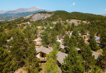 Vista aerea dei lodge Villatent Nomad al Camping La Presqu’île in Francia, tra alberi e montagne verdi.