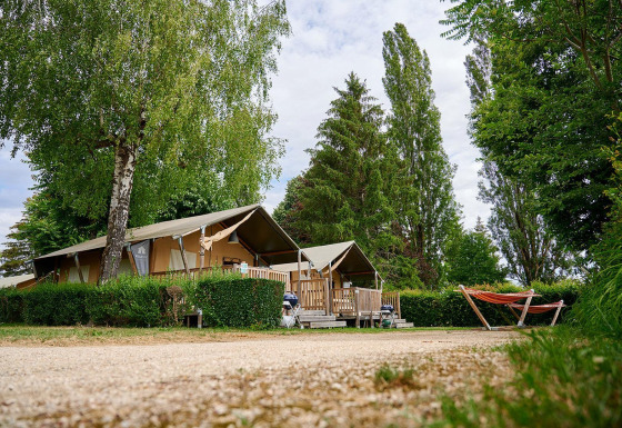 Safaritent Villatent Wood op Camping Le Coin Tranquille in Frankrijk, omringd door bomen en een oranje hangmat.