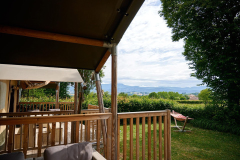 Vista desde la terraza de una tienda safari en Villatent Wood, Camping Le Coin Tranquille, Francia, con naturaleza.