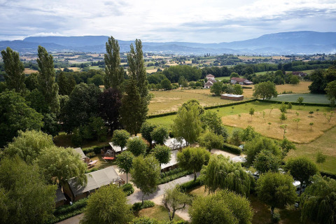 Vista aérea de la tienda safari Villatent Wood en Camping Le Coin Tranquille en Francia, rodeada de campos.