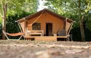 Safari telt Villatent Nomad med træterrasse og hængekøje på Camping La Garenne i Frankrig omkranset af træer.