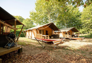 Tiendas safari Villatent Nomad en Camping La Garenne, Francia, rodeadas de árboles y con terrazas de descanso.