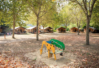 Tiendas safari Villatent Nomad en Camping La Garenne en Francia, rodeadas de árboles y un parque infantil.